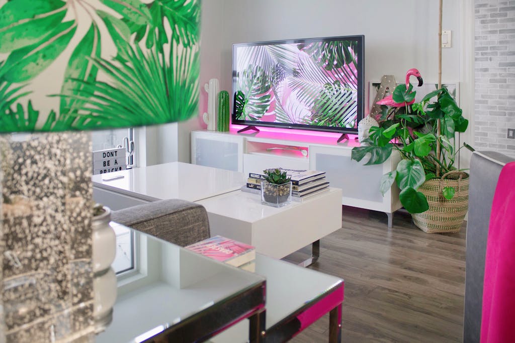 A stylish living room featuring tropical-themed decor, plants, and a modern TV setup.