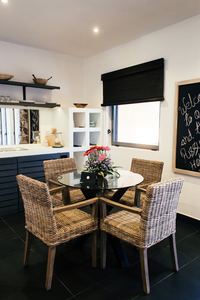 Elegant dining area featuring a glass table and woven chairs in a contemporary home setting.