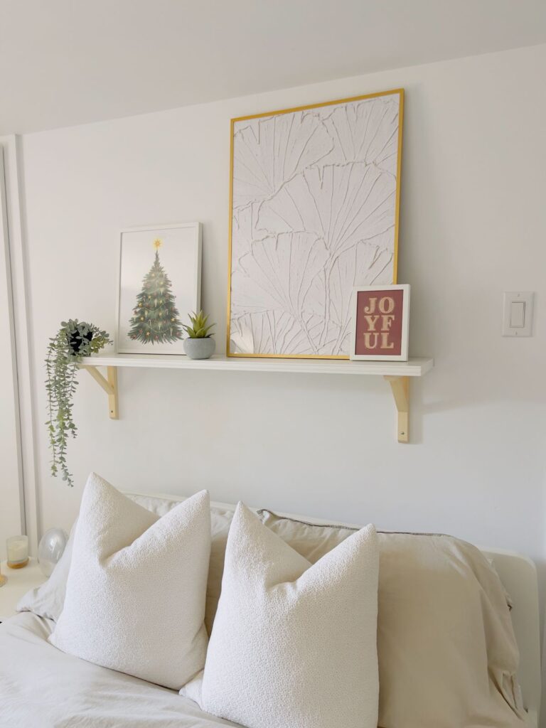 A small bedroom with a shelf above the bed.